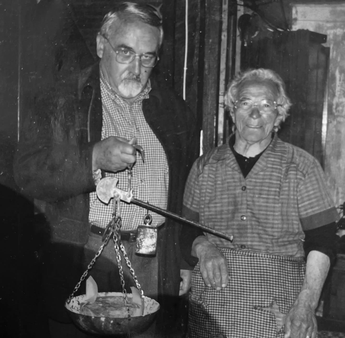 Pareja de antepasados con báscula romana pesando queso